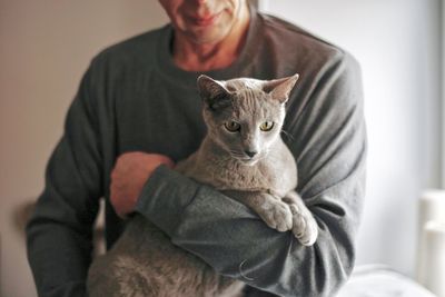 Midsection of man with cat at home