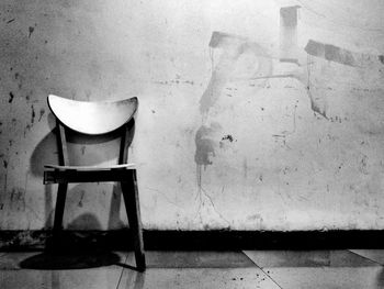 Empty chairs and table against wall