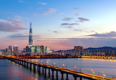 Illuminated city buildings against sky during sunset