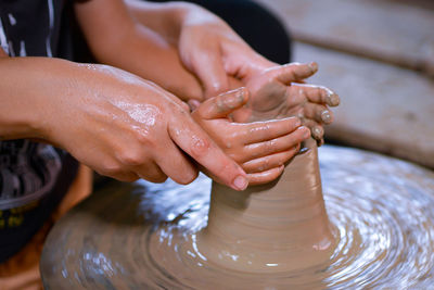 Midsection of people working on pottery wheel