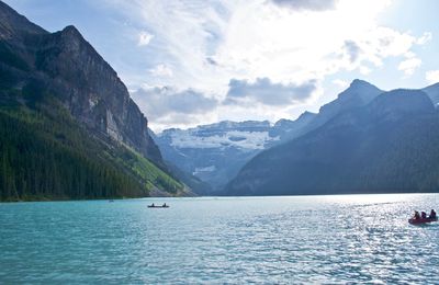 High angle view of people boats sailing in lake by mountains against sky