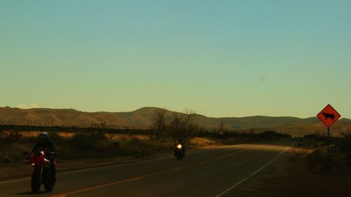 Country road leading towards mountains against sky