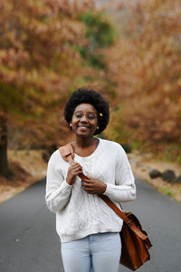 Woman holding smiling while standing against blurred background