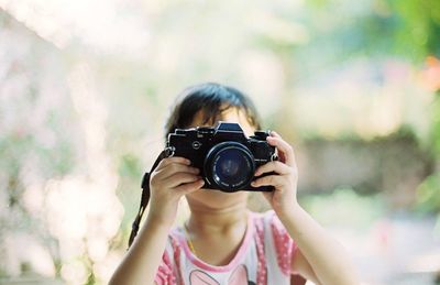 Close-up of girl photographing with camera while standing outdoors