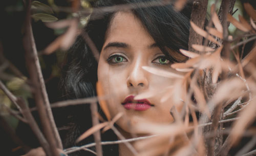 Close-up portrait of young woman looking through plants