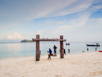 Rear view of people at beach against sky