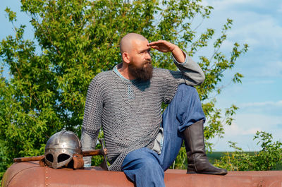 Emotional photo of medieval viking in metal chain mail, looking anxiously into the distance. 