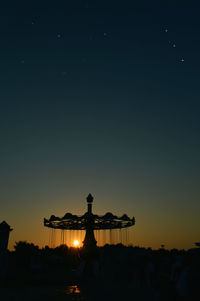 Silhouette amusement park ride against sky during sunset