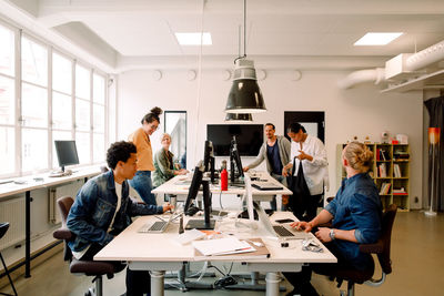 Creative male and female business colleagues working in open plan office