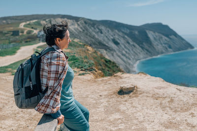 Adult woman backpack went hiking in mountains near the sea in summer, spring sunny day for health