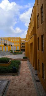 Footpath amidst buildings against sky