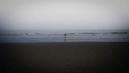 Silhouette person standing on beach against clear sky