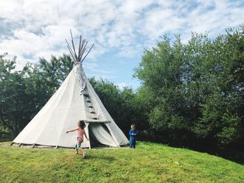 Siblings camping at park against sky