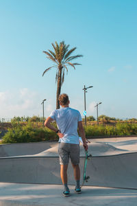 Rear view of man standing by palm trees against sky