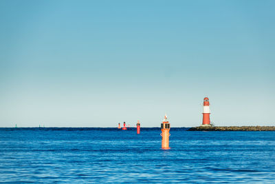 Lighthouse by sea against clear sky