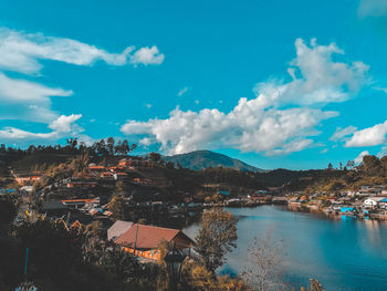 Panoramic view of townscape by mountains against blue sky