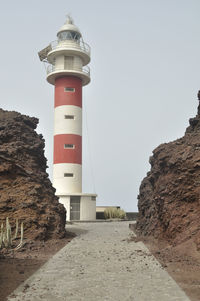 Lighthouse by sea against clear sky