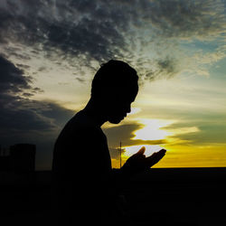 Silhouette man using smart phone against sky during sunset