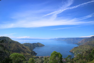 Scenic view of sea and mountains against blue sky