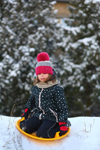 Winter portrait of a girl with a plastic sled sliding on a snowy slope 