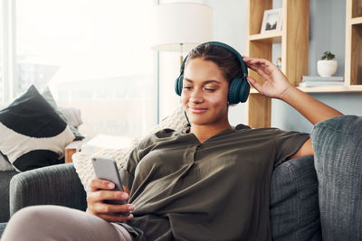 Young woman using mobile phone while sitting on laptop