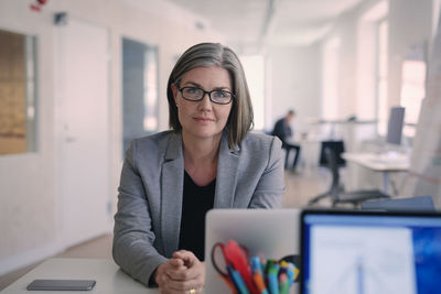 Portrait of confident mature businesswoman sitting at desk in office