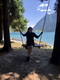 Full length of woman standing on lakeside against sky 