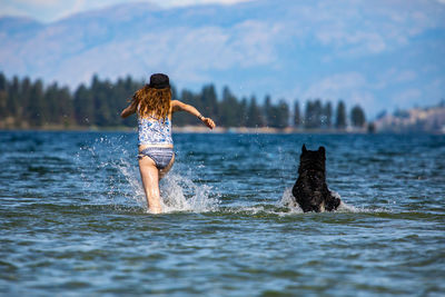 Rear view of woman with dog at sea