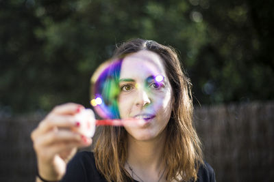 Portrait of young woman playing with bubble