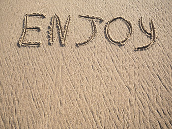 Enjoy word is written on the beach sand with copy space