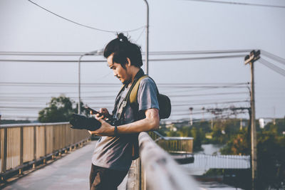 Full length of young woman on footbridge against sky in city