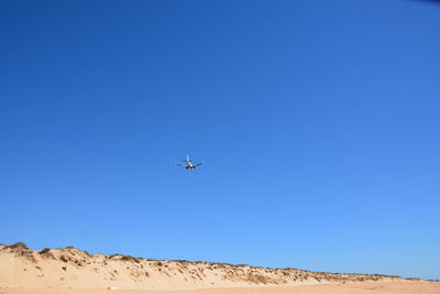 Low angle view of helicopter against clear blue sky