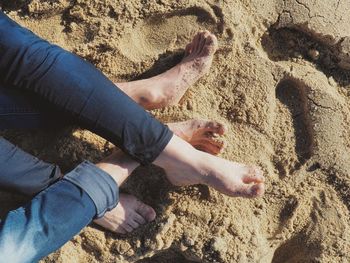 Low section of people relaxing on sand at beach