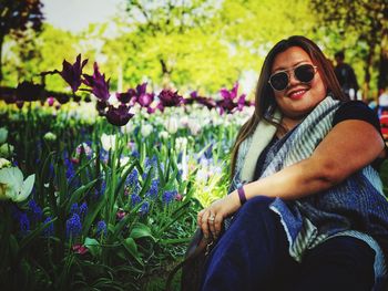 Portrait of smiling young woman wearing sunglasses sitting on land