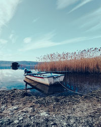 Boat moored on shore against sky