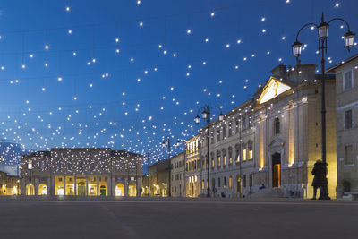 Illuminated street amidst buildings in city at night