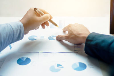 Midsection of man holding paper on table