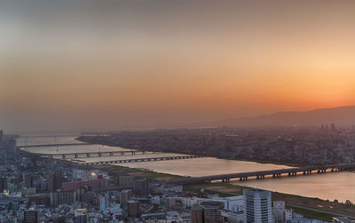 High angle view of river and buildings against sky at sunset