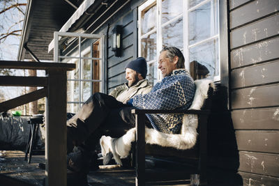 Happy mature friends sitting together at front porch in winter