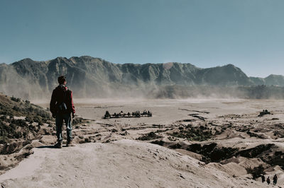 Rear view of man on rock against sky