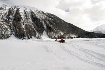 A red airport helicopter in the snow in the alps switzerland