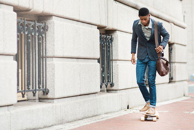 Man with bag skateboarding at street