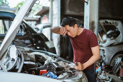 Side view of man repairing car