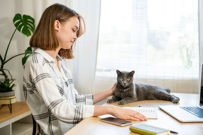 Young woman working on laptop at home. cozy home office workplace, remote work or learning concept.