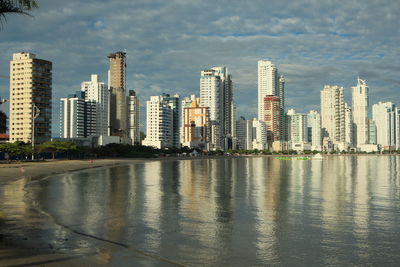 Sea by cityscape against sky