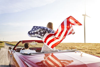 Rear view of flags sitting on car against sky