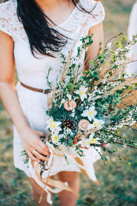 Close-up of bride holding flowering plants with basket