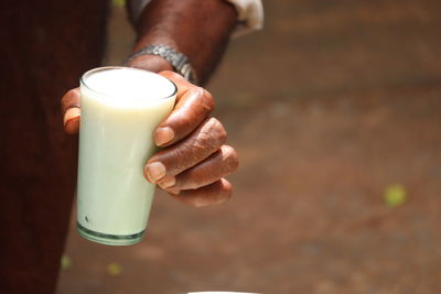 Midsection of man holding a glass of sweet curd