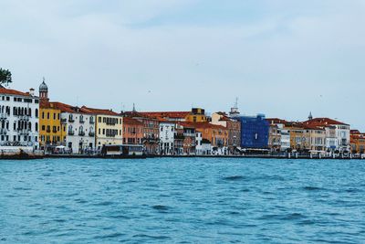 Canal by buildings in town against clear sky