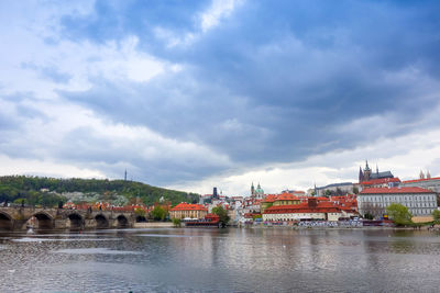 Charles bridge over vltava river against cloudy sky